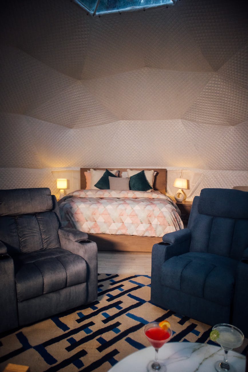 Stylish dome room interior with a cozy bed, recliners, and a cocktail on the table.