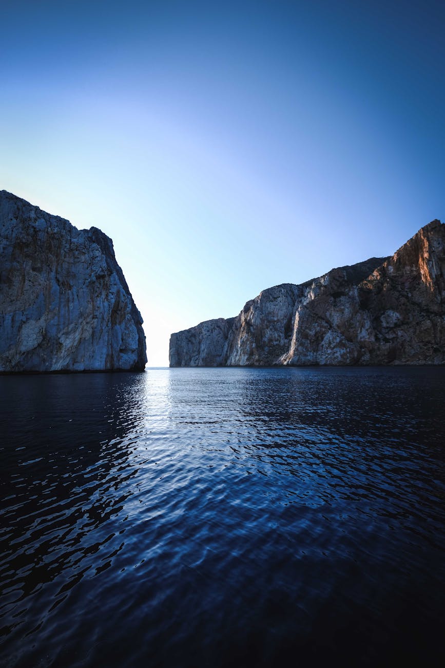 Majestic cliffs tower over a calm blue sea, creating a breathtaking coastal scene during daylight.