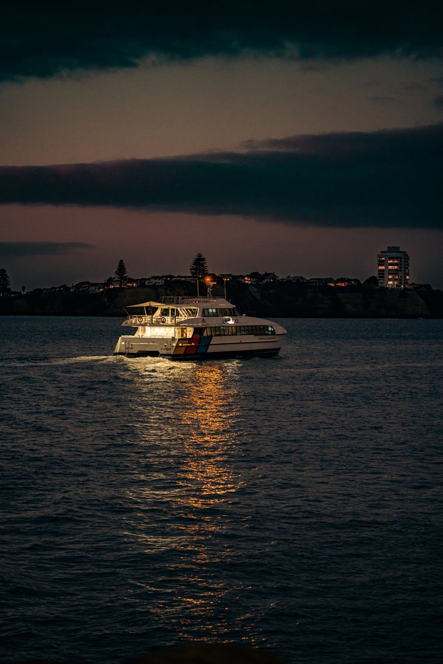 A serene scene of a boat illuminated against the night sky in Auckland Harbour, New Zealand.