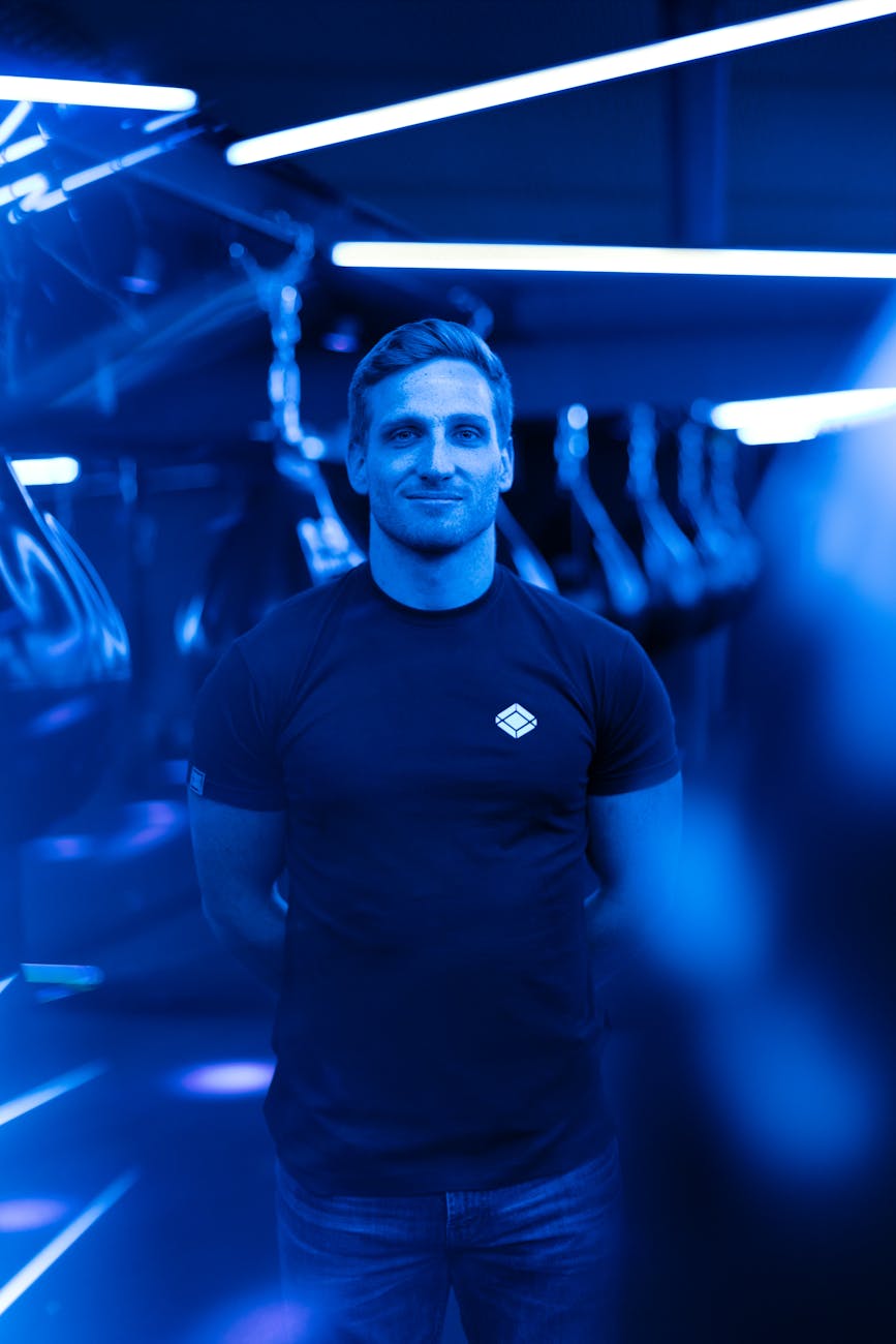 Portrait of a male gym trainer under vibrant blue neon lights in a modern gym.