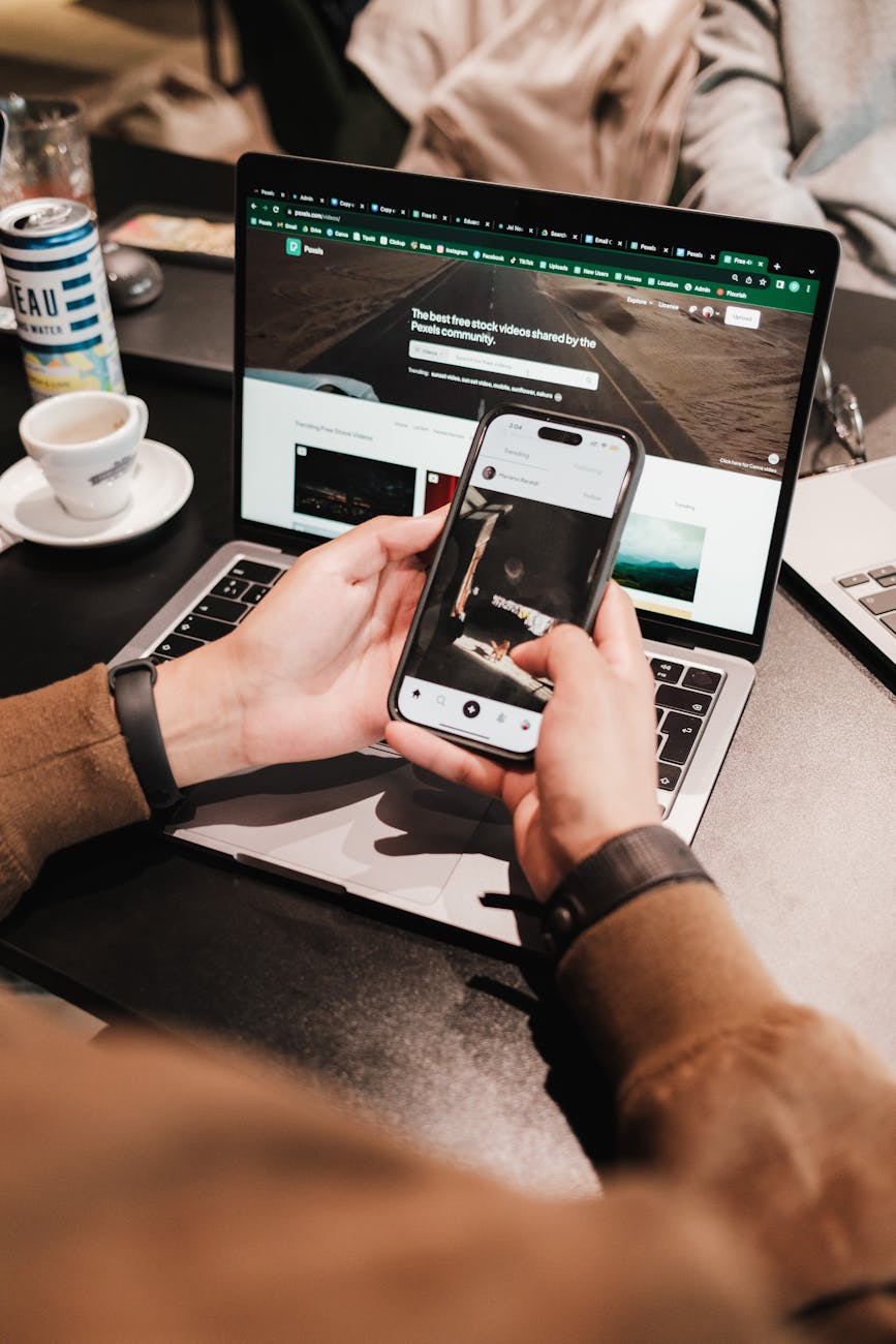 Person using a smartphone and laptop simultaneously, showcasing multitasking in technology.