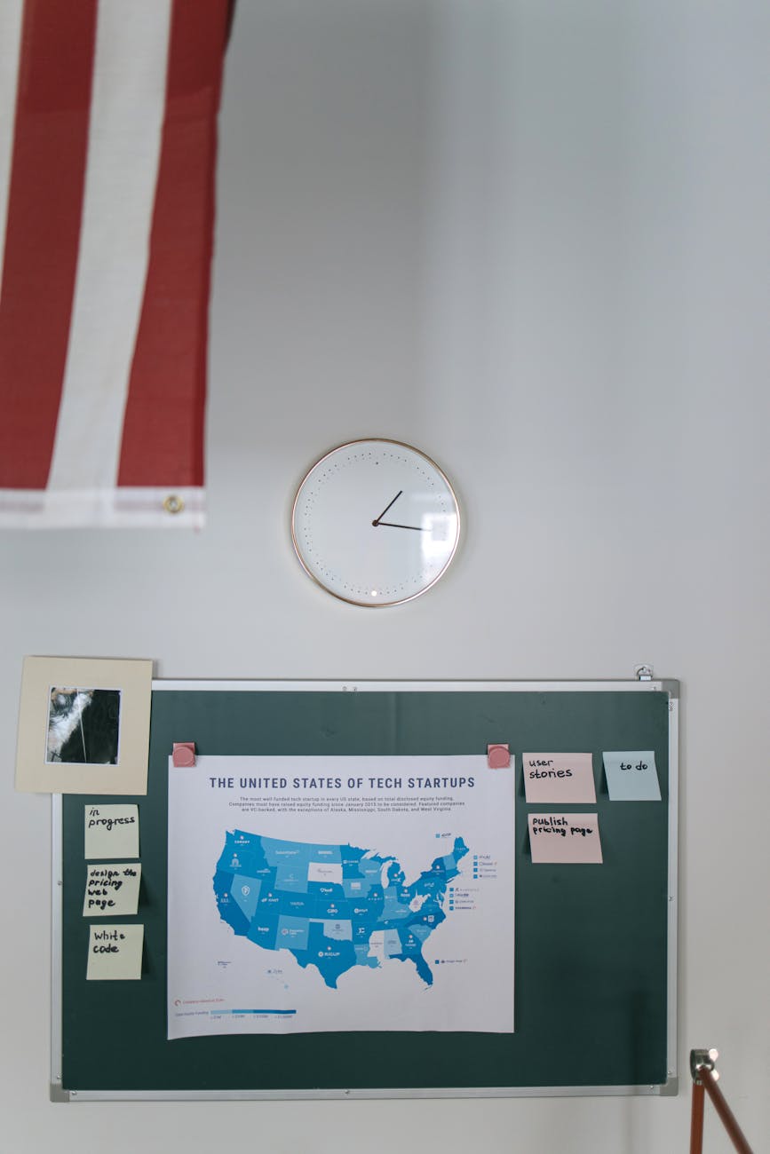 United States tech startup map on chalkboard in office with clock and American flag.