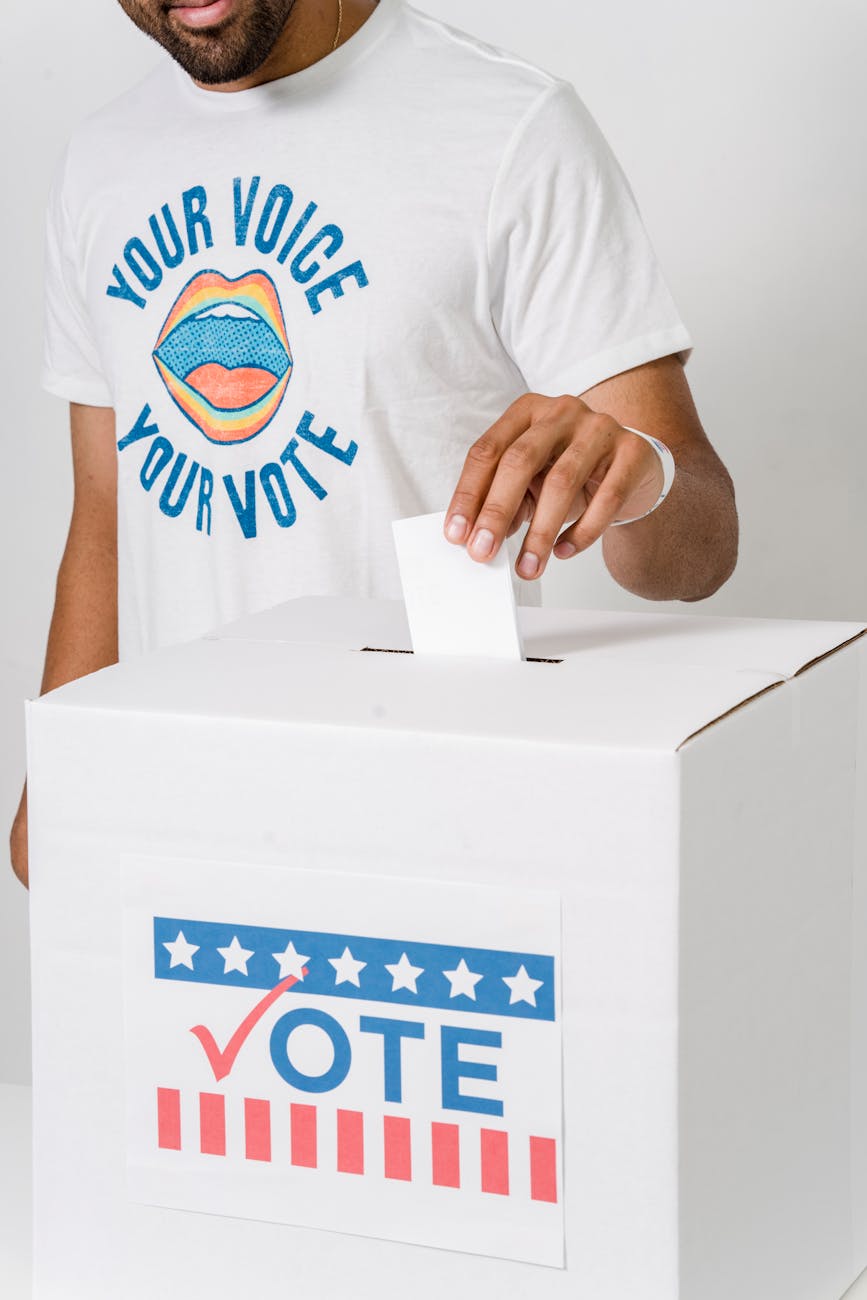 Close-up of a person placing a vote into a ballot box, highlighting voter participation.