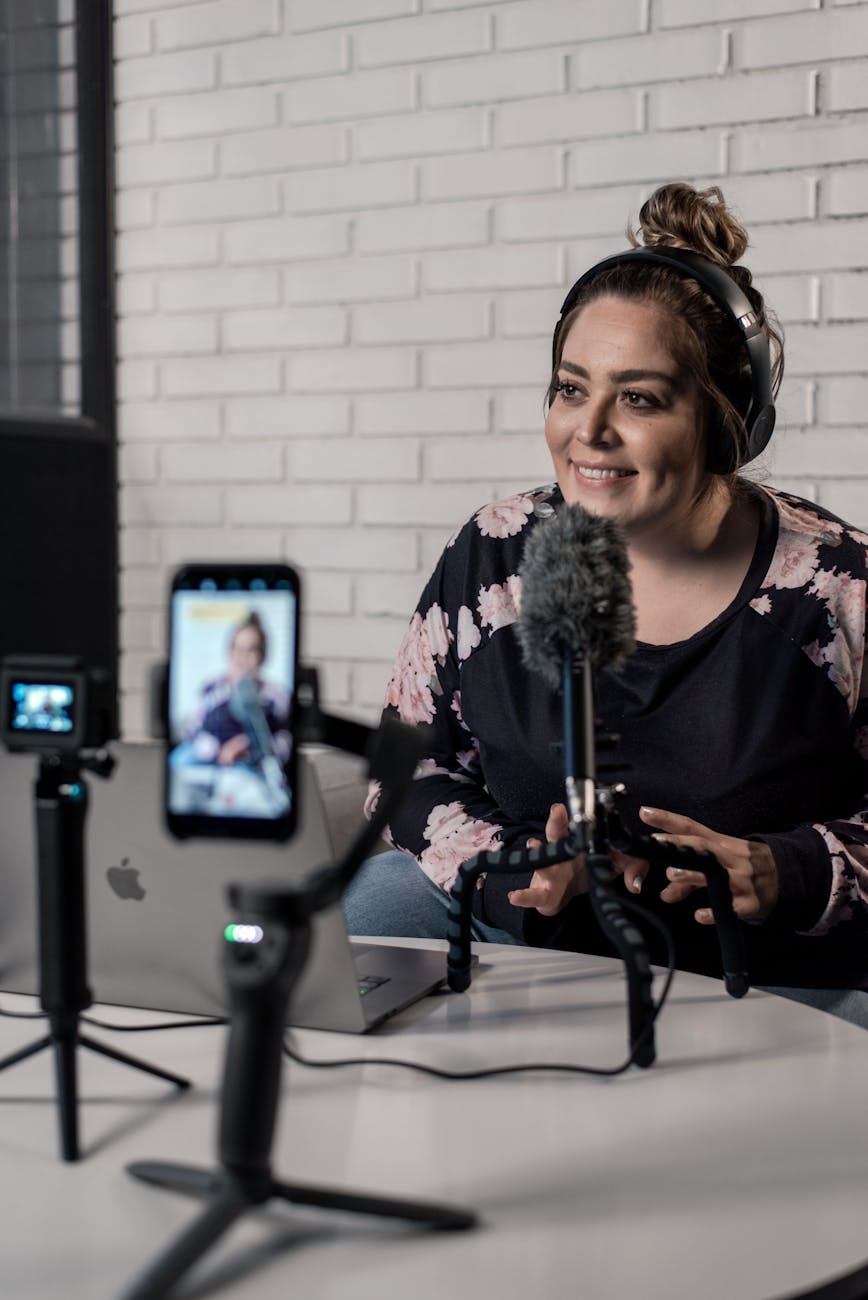 Woman recording video podcast with microphone and camera setup in modern studio.