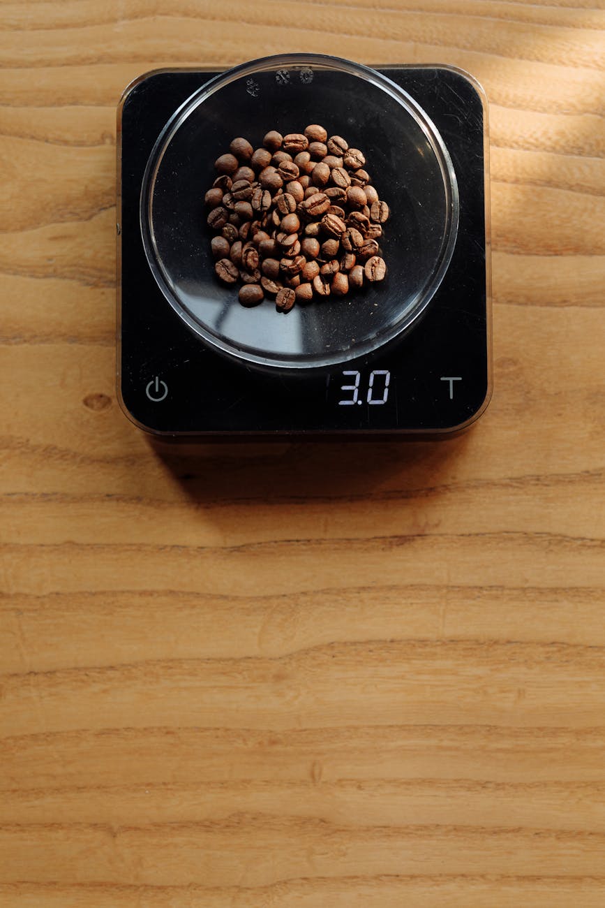 Coffee beans measured on a digital scale placed on a wooden surface.