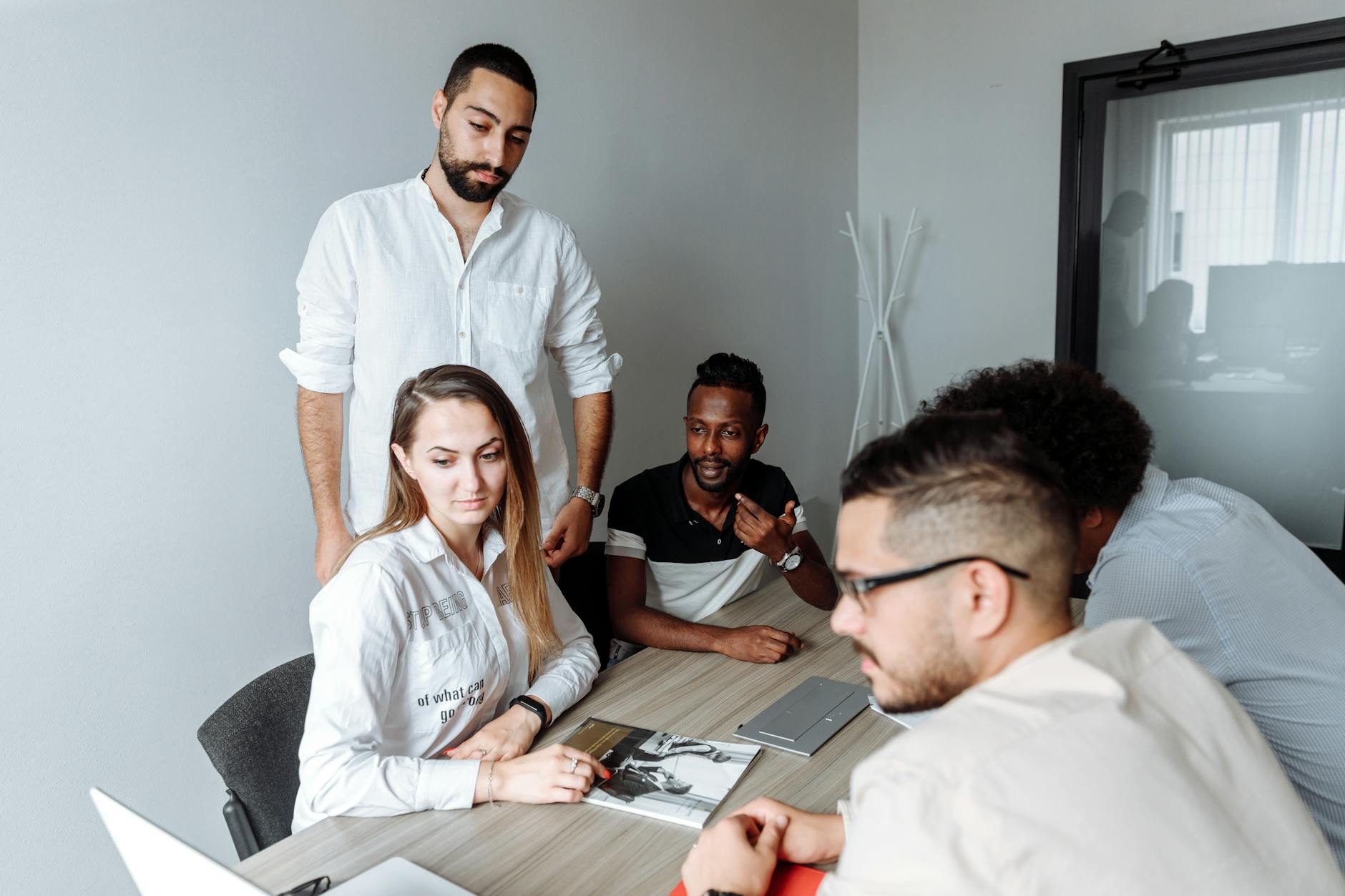 A group of diverse colleagues engaged in a business meeting around a shared office table.