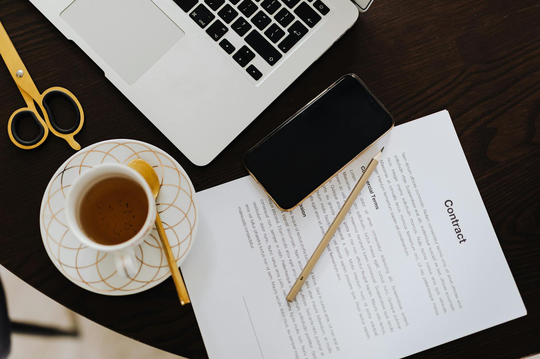 Top-view of a workspace with contract, coffee, laptop, and smartphone focused on business productivity.