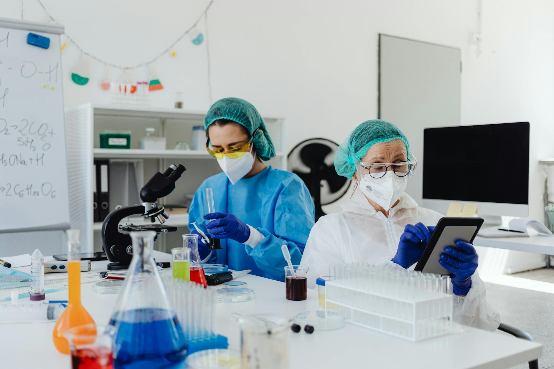 Researchers conducting experiments in a laboratory, using microscopes and digital tablets.