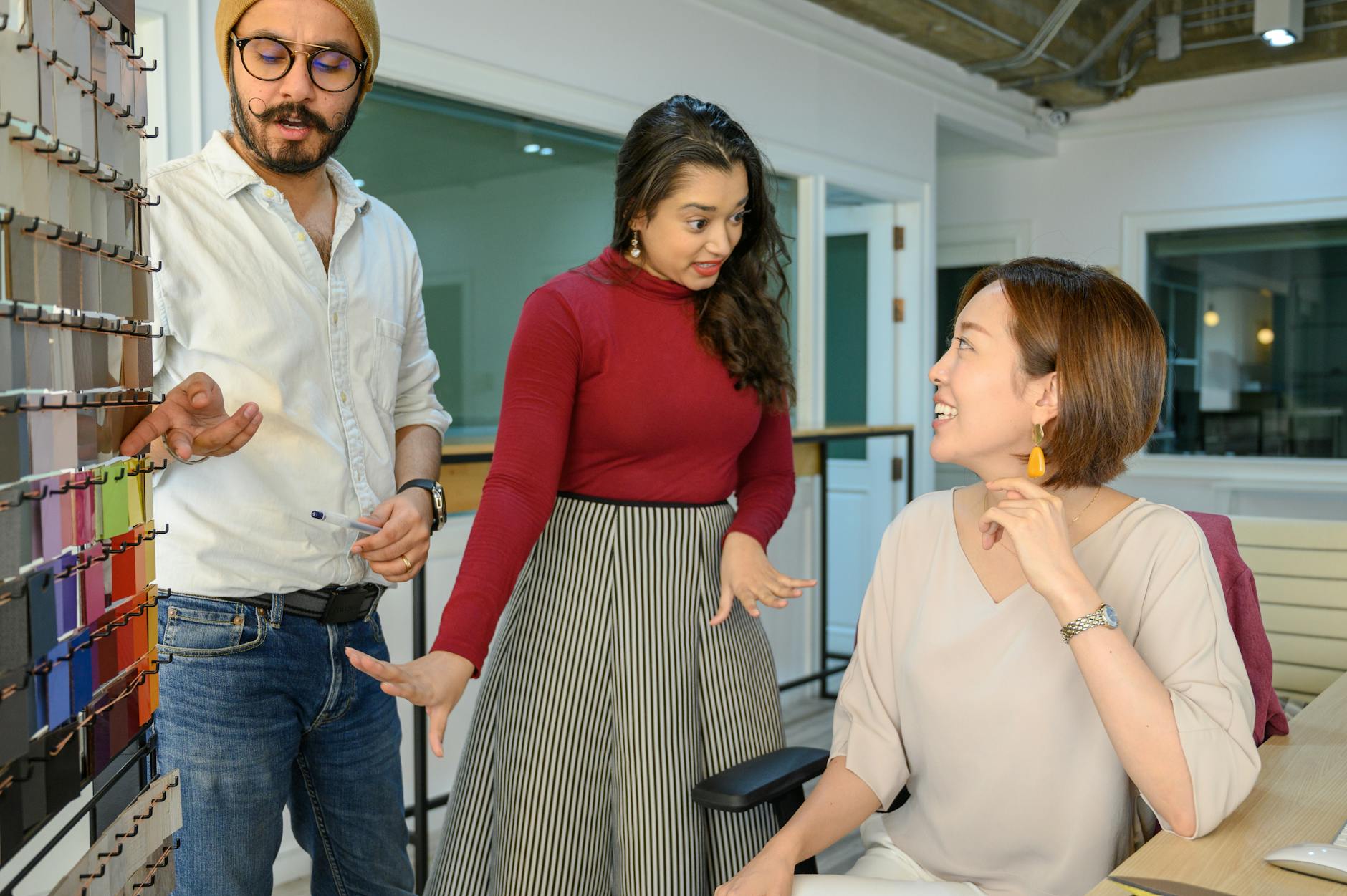 A diverse team discusses color swatches in an office setting for a project.