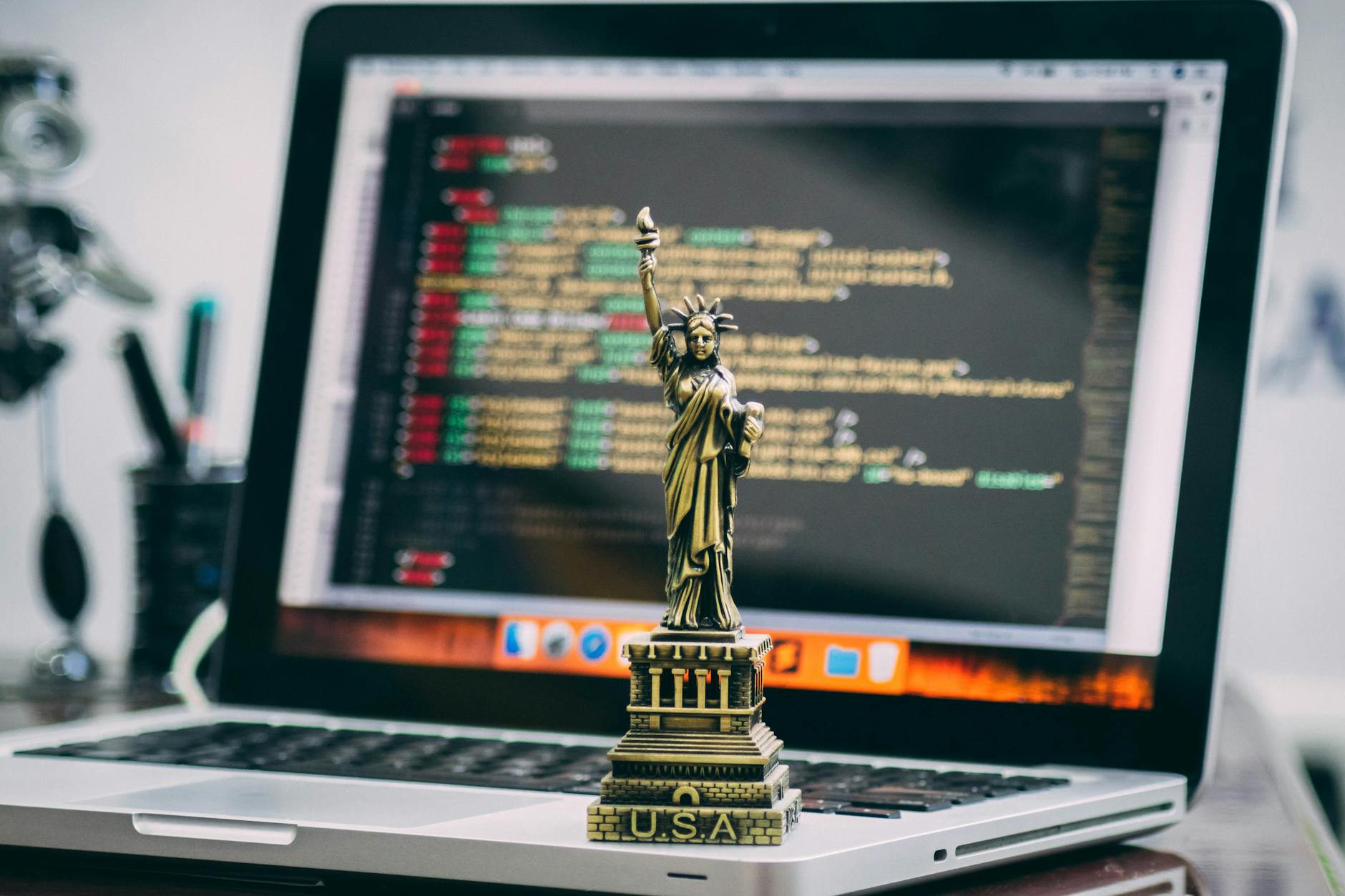 A miniature Statue of Liberty placed on a laptop displaying code, symbolizing freedom in technology.